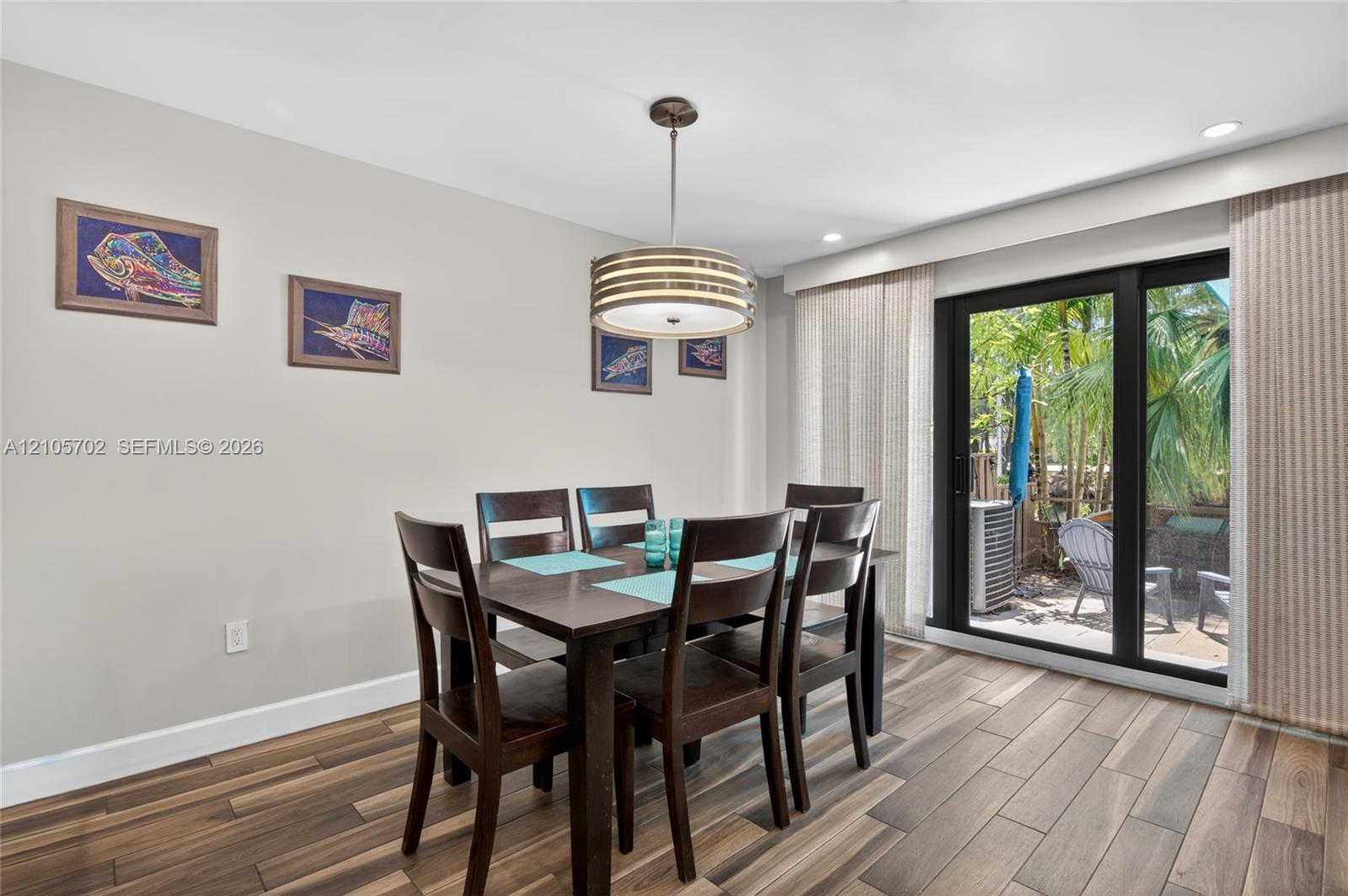 Wood-finish flooring, recessed lighting, tiered drum pendant fixture, and sliding glass door with exterior access