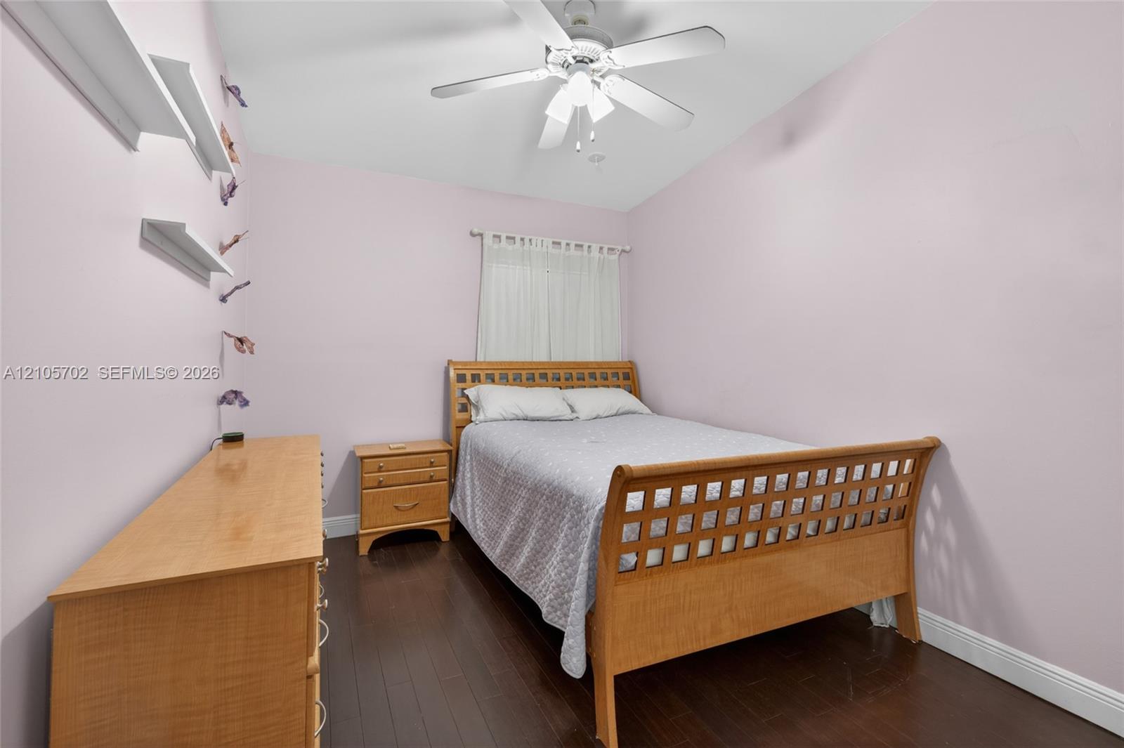 Dark-toned wood-finish flooring, ceiling-mounted paddle fan, and wall-mounted shelving