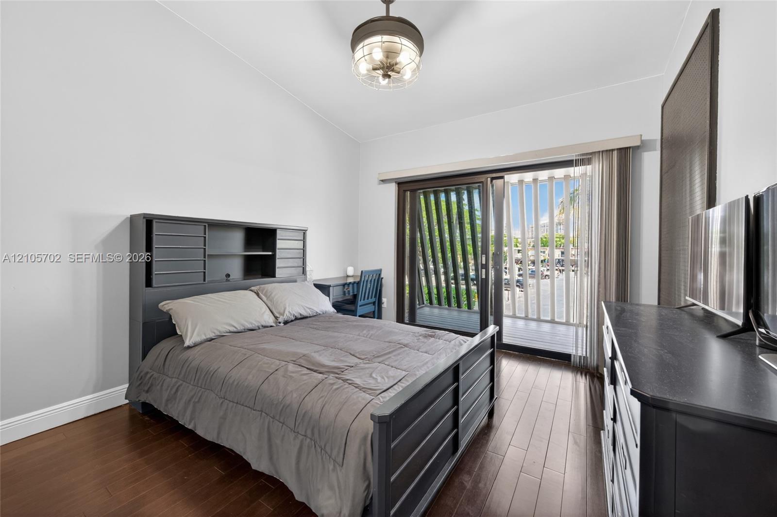 Wood-finish flooring, vaulted ceilings, and sliding glass doors with exterior balcony access
