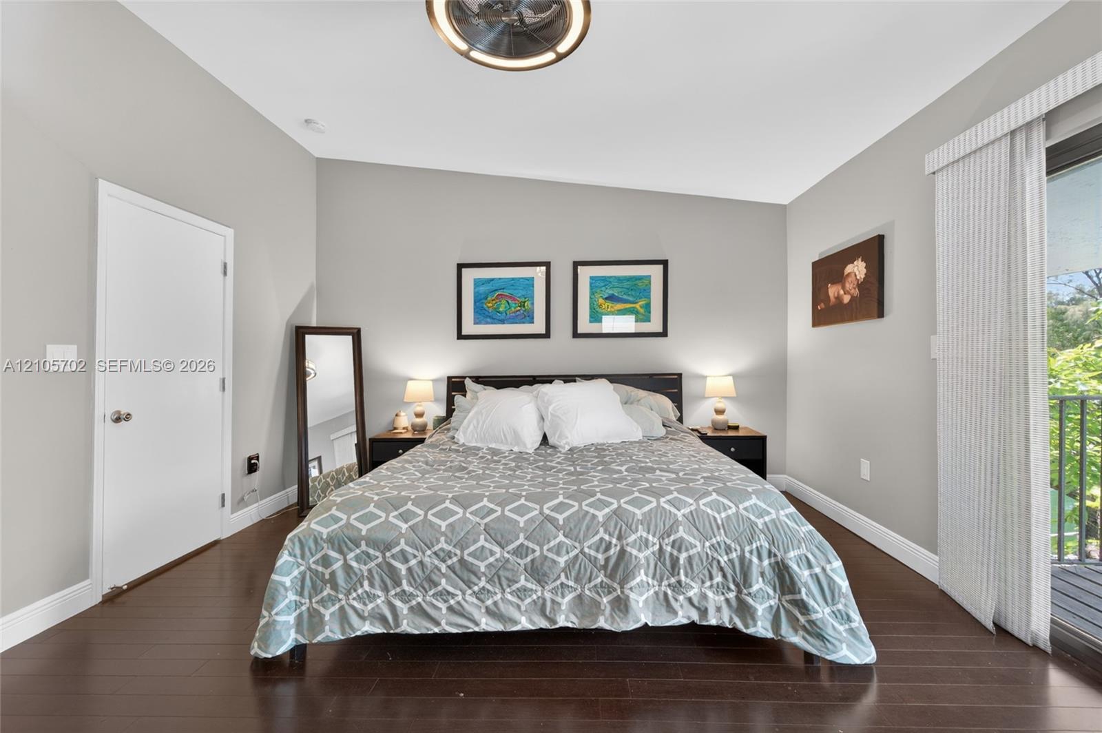 Vaulted ceiling featuring a central light fixture, dark wood-finish flooring, neutral wall tones, and glass sliding doors