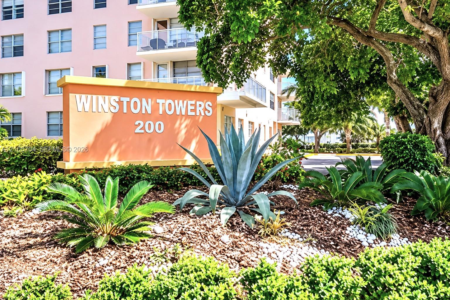 Winston Towers 200 exterior signage featuring native landscaping, mature tree canopy, and mulch-based garden beds