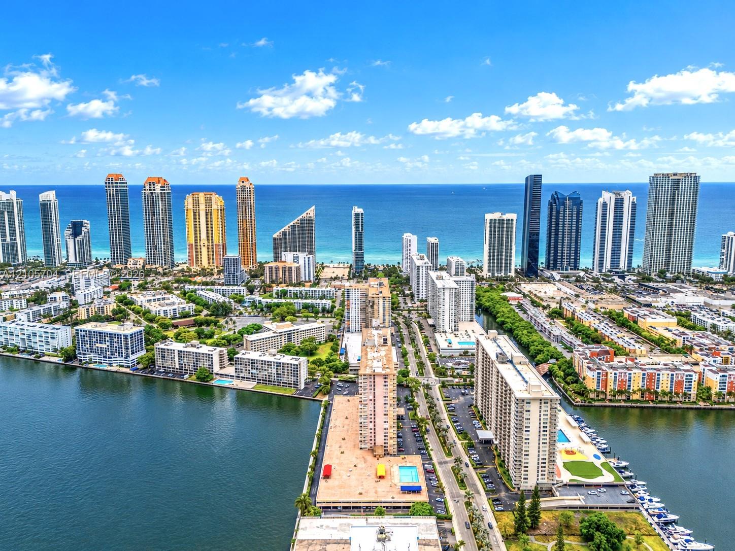 Aerial perspective of coastal high-rise development featuring direct waterfront access, boat slips, outdoor swimming pools, and proximity to the Atlantic Ocean