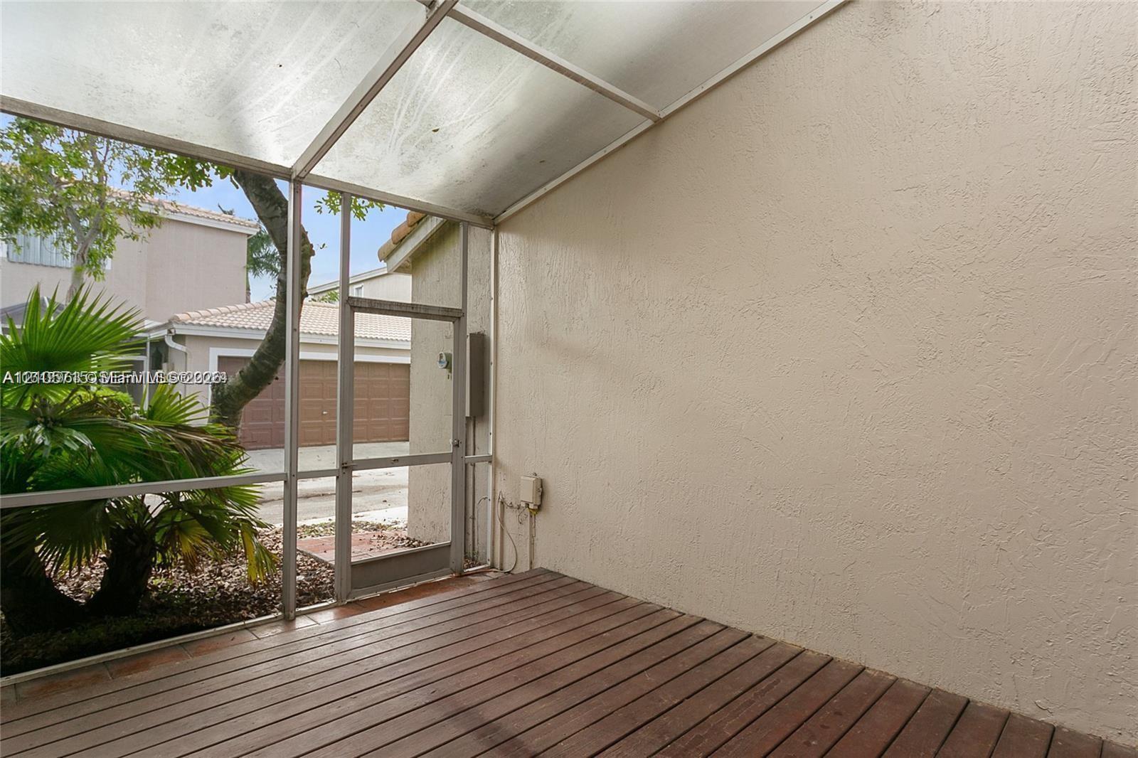 Screened patio featuring wood-finish flooring, a translucent roof panel, and stucco walls