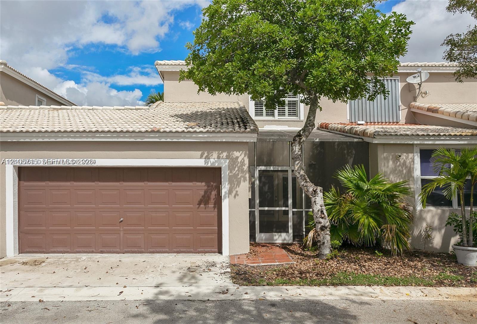 Stucco exterior featuring a tiled roof, attached garage with sectional door, and screened entry