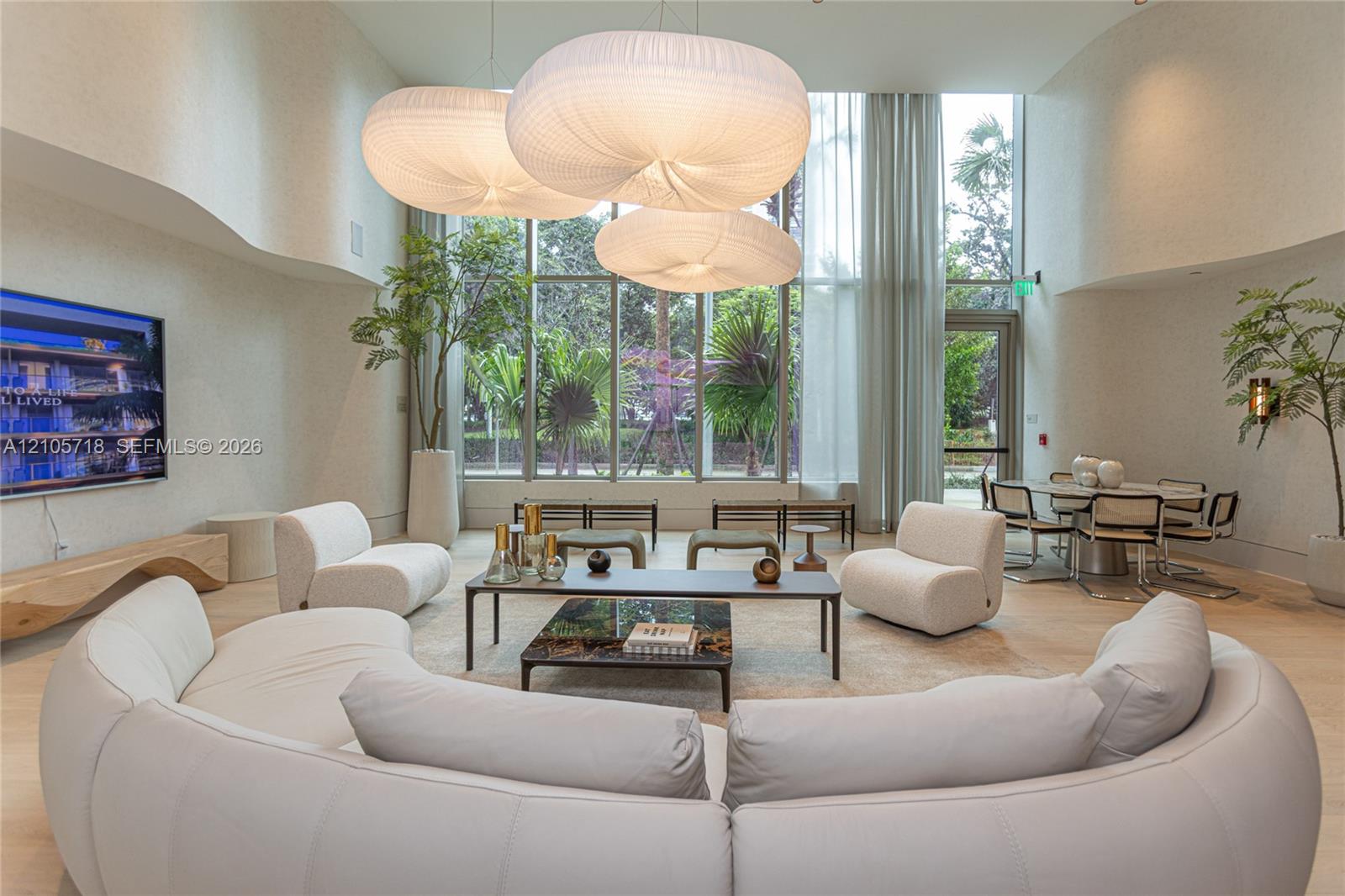 Double-height ceilings, floor-to-ceiling windows, sculptural fabric pendant lighting, curved wall architecture, and light-toned flooring
