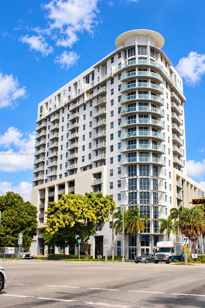 High-rise exterior featuring curved glass balconies, concrete facade, and a tiered architectural roofline