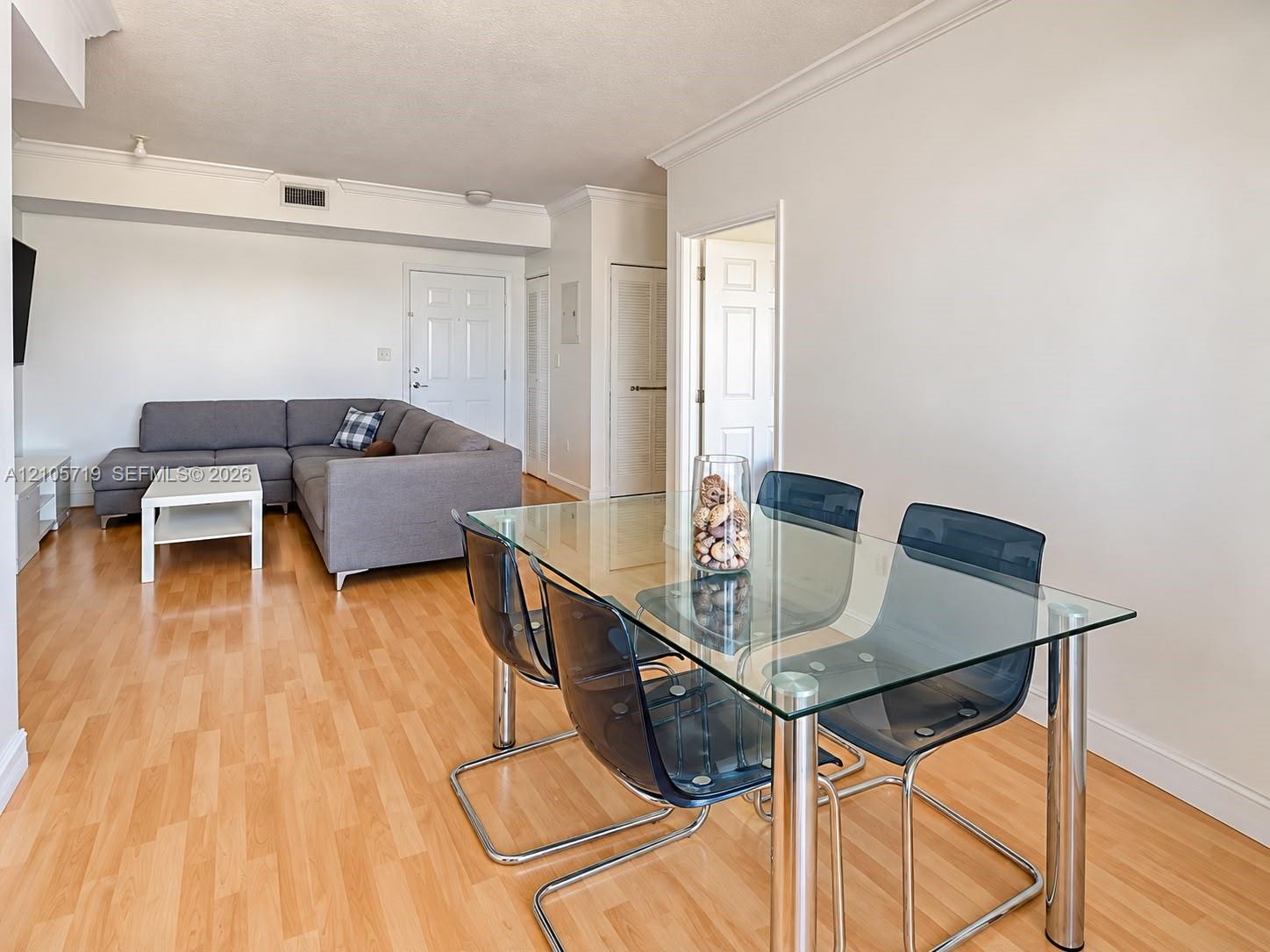 Interior space featuring wood-finish flooring, crown molding, six-panel interior doors, and a neutral color palette