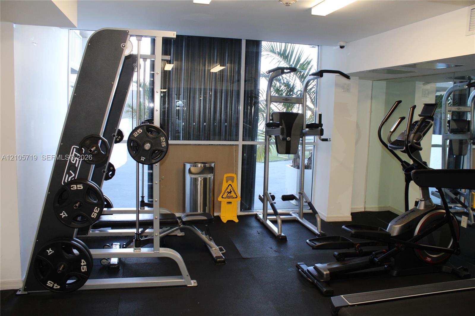Fitness center featuring rubberized flooring, mirrored walls, and floor-to-ceiling windows