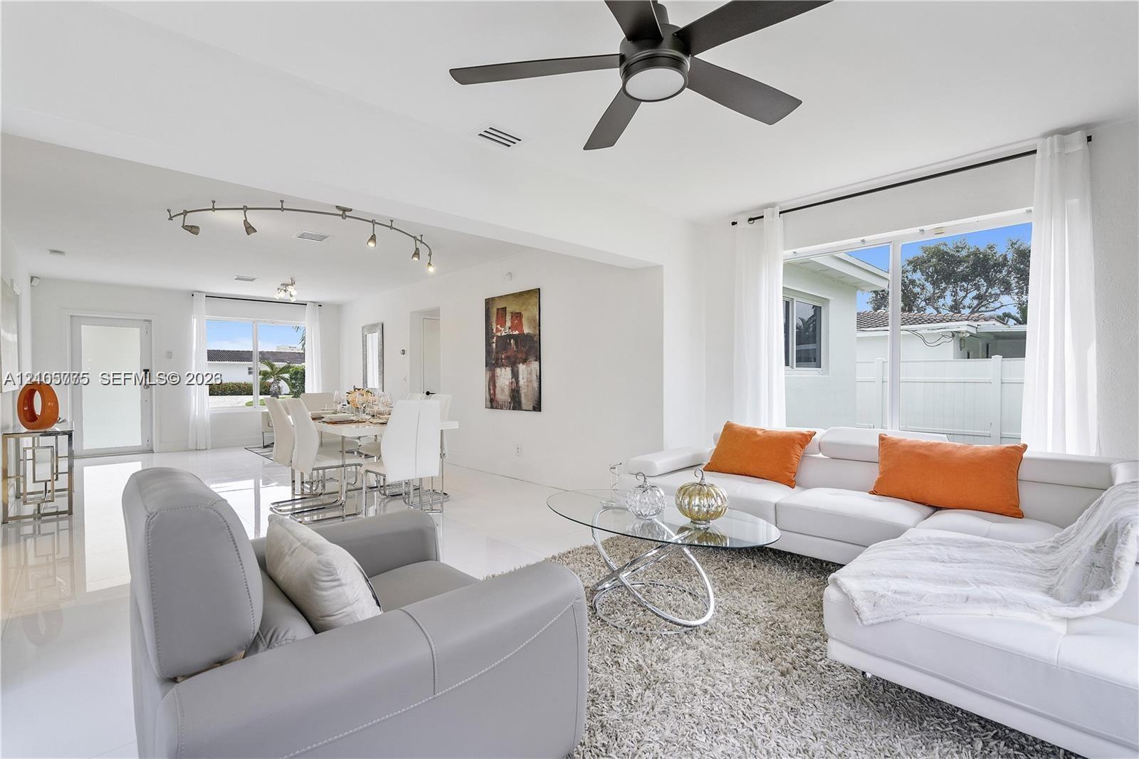 Open-concept interior featuring large-format tile flooring, matte black ceiling fan, and adjustable track lighting