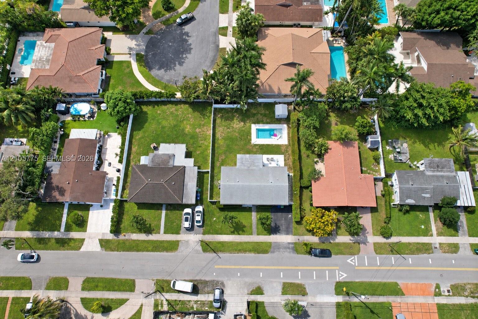 Aerial perspective of a residential property featuring an in-ground swimming pool, a fenced backyard, and a paved driveway