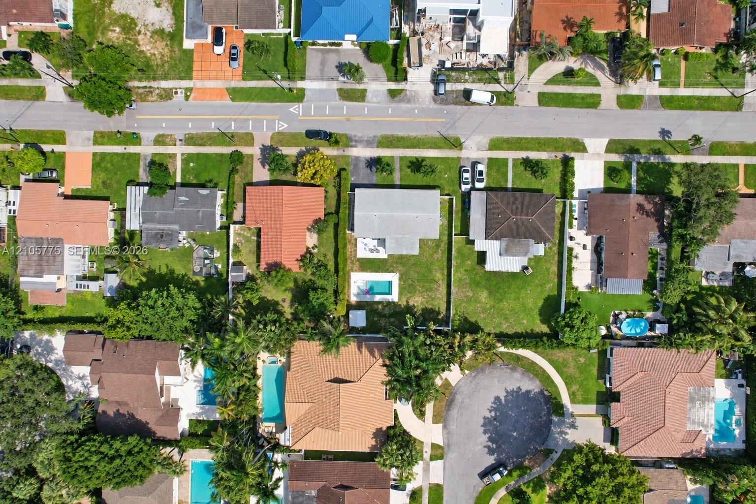 Aerial perspective of a single-family property featuring a rectangular in-ground swimming pool, a fully fenced backyard, and a concrete driveway