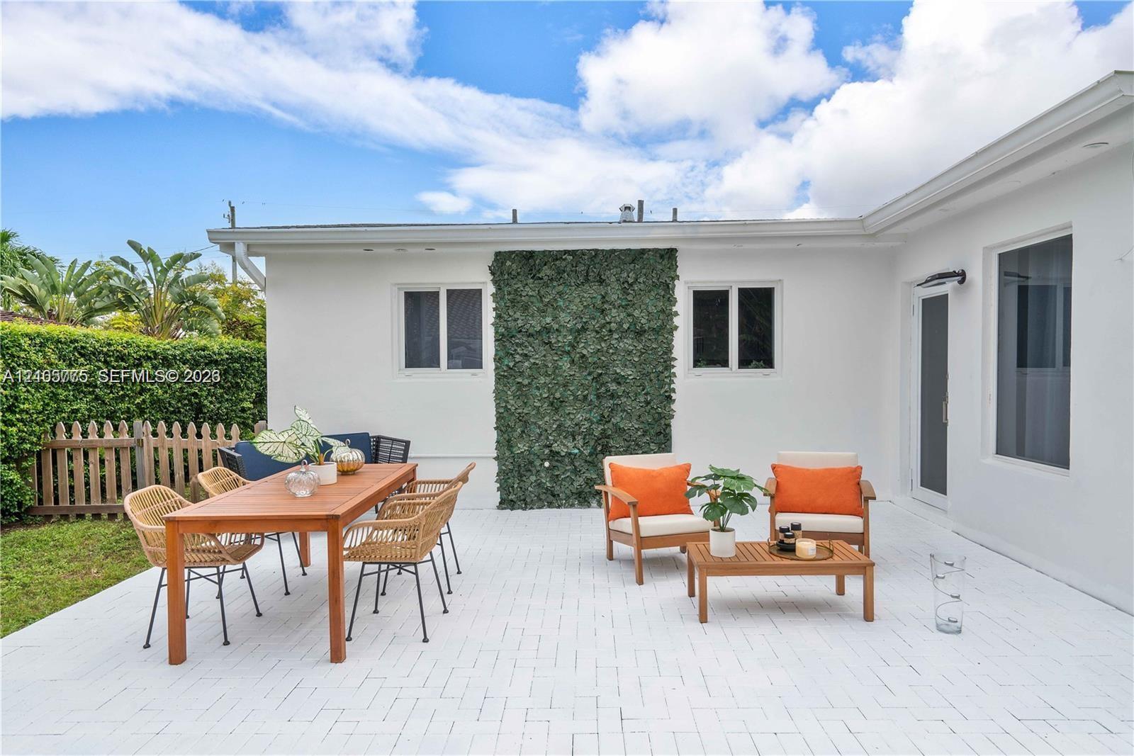 Outdoor patio featuring white brick pavers, a vertical exterior green wall, and a wood picket fence enclosure