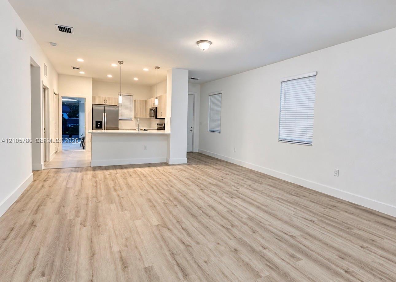 Open-concept floor plan featuring wood-finish flooring, recessed lighting, a breakfast bar, and stainless steel kitchen appliances