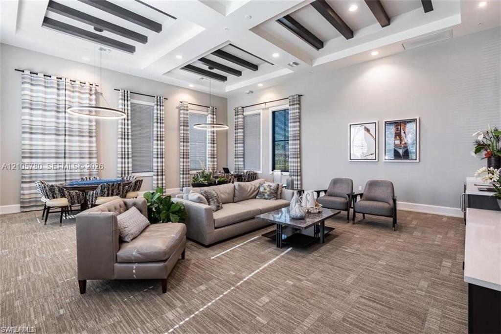 Expansive room featuring recessed tray ceilings with dark-finished coffered beams, integrated recessed lighting, high-reaching windows, and modern circular pendant light fixtures