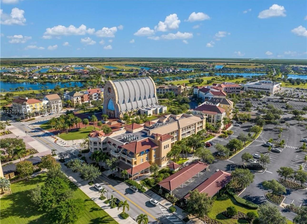 Aerial perspective featuring multiple low-rise structures with tile roofing, surface parking areas, landscaped grounds, and paved walkways