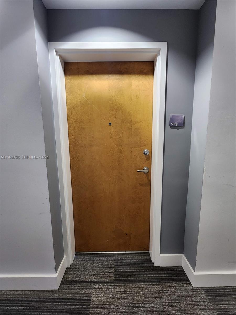 Solid-core wood-finish door with brushed metallic hardware, integrated security peephole, and white architectural casing