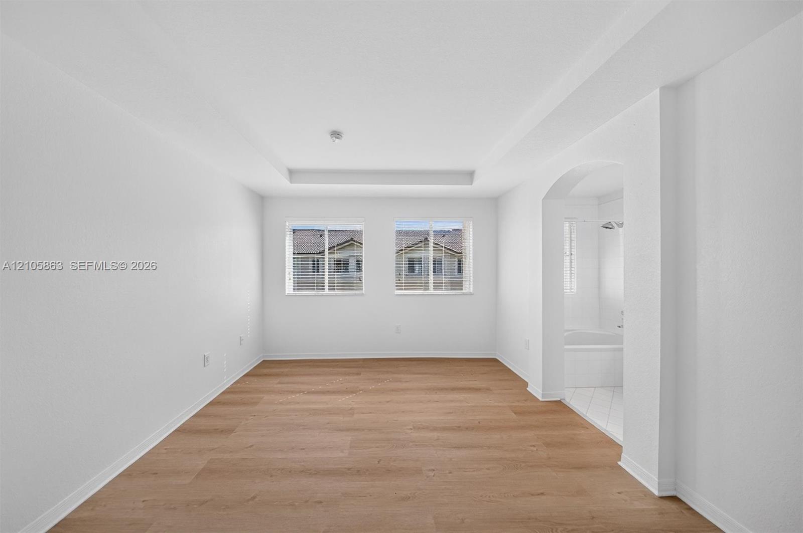 Interior space featuring wood-finish flooring, a recessed tray ceiling, and dual windows