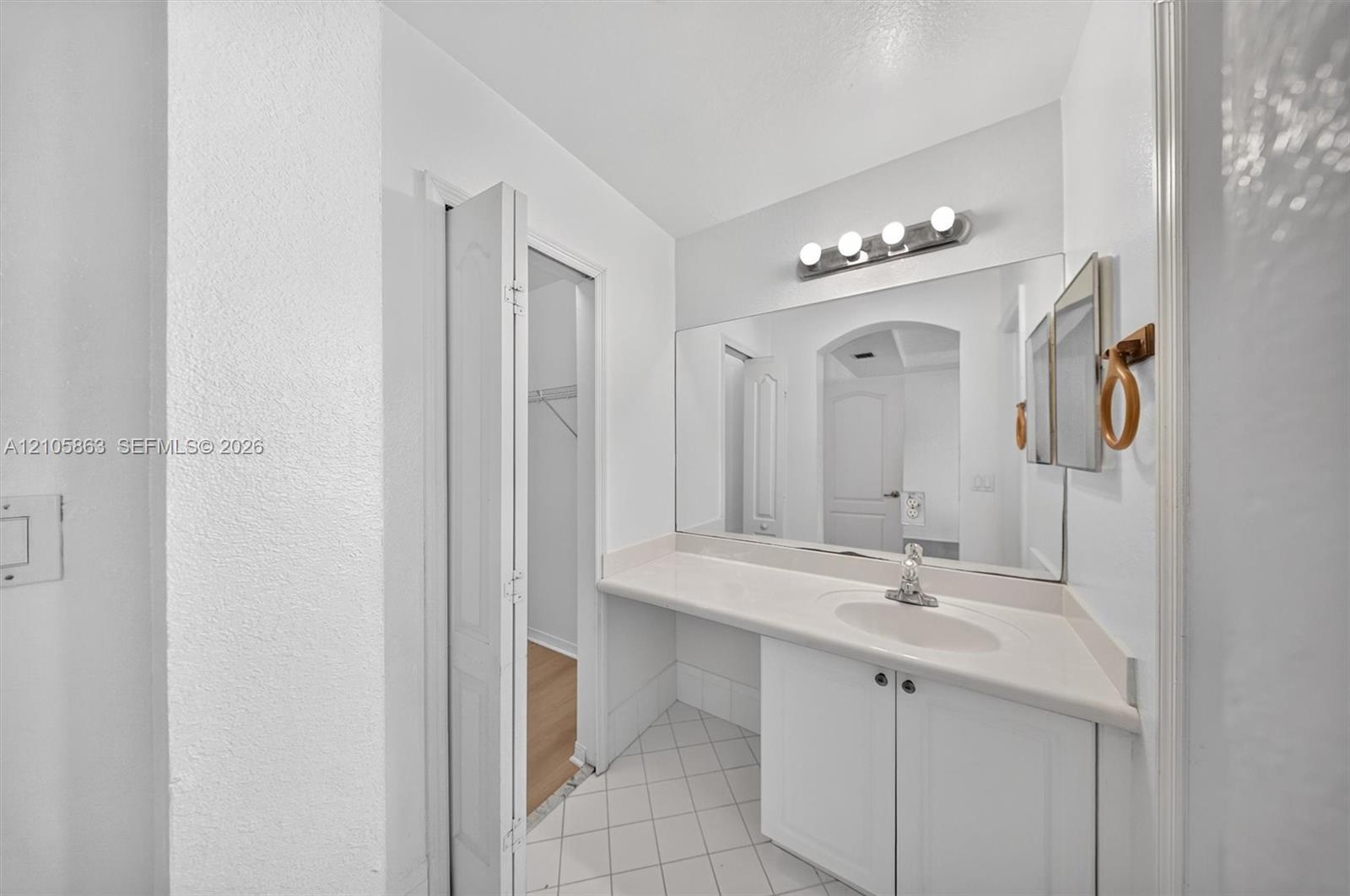 Bathroom featuring a vanity with a solid-surface countertop, an integrated oval sink, a large wall-mounted mirror, and tile flooring laid on a diagonal