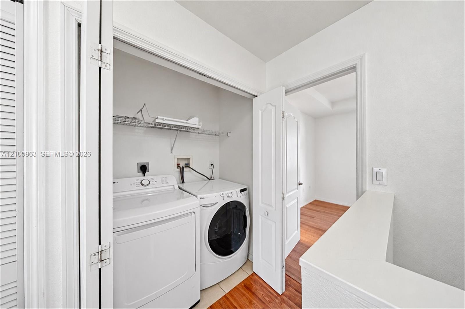 Dedicated laundry closet featuring wire shelving, side-by-side appliance hookups, and bi-fold door entry
