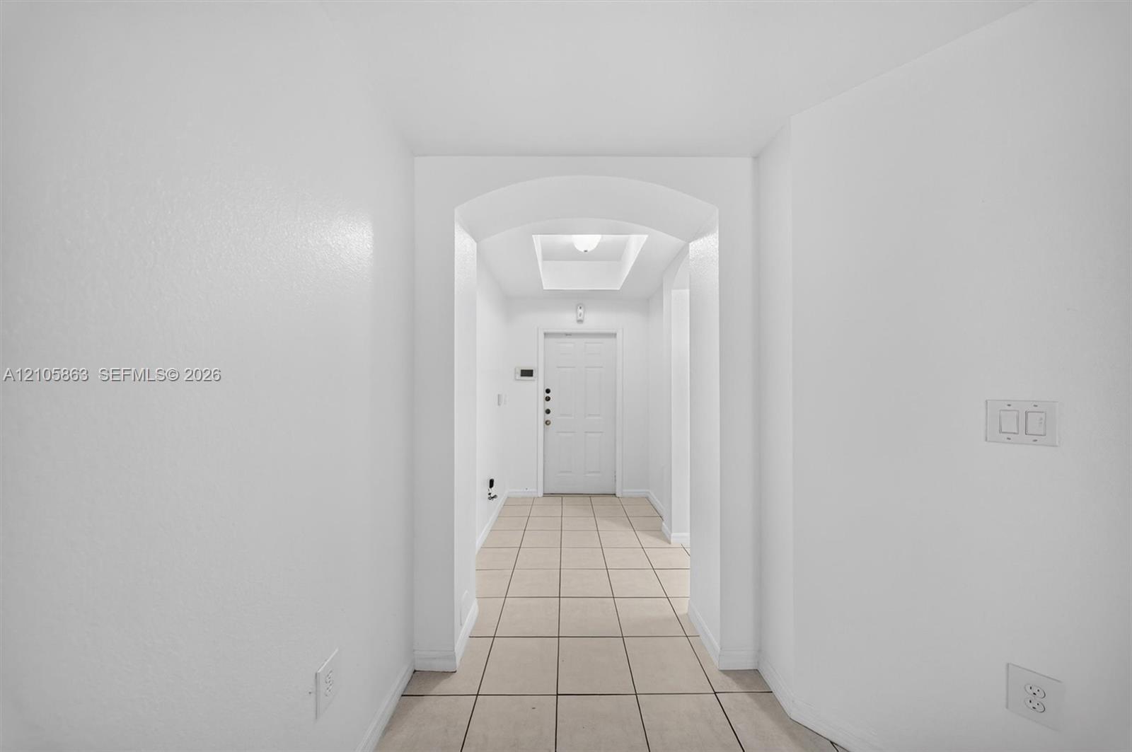 Entryway featuring tile flooring, an arched threshold, a recessed ceiling tray, and a paneled entry door