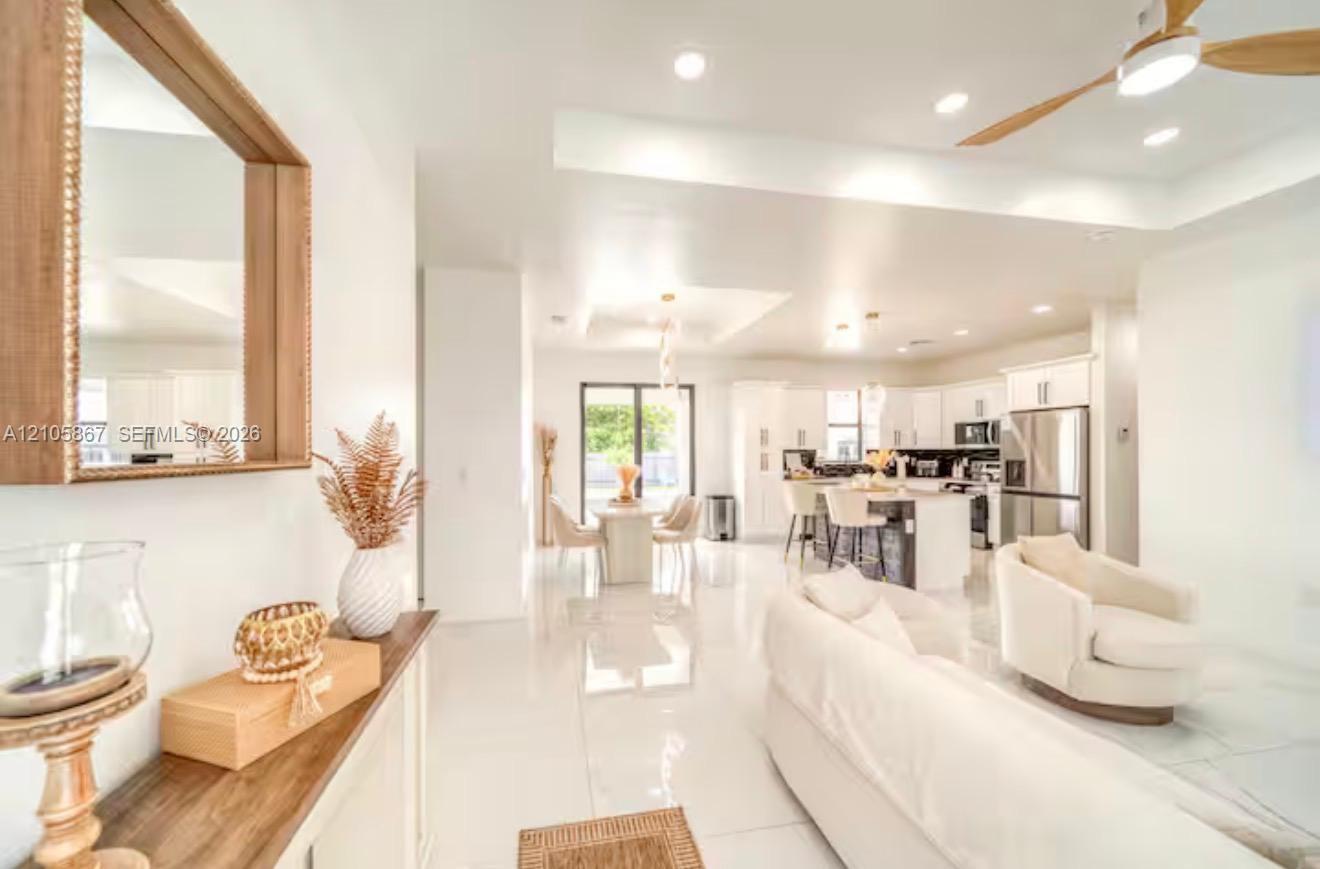 Open floor plan featuring recessed lighting, tray ceilings, polished tile flooring, and a kitchen equipped with a center island and stainless steel appliances Open floor plan featuring recessed lighting, tray ceilings, polished tile flooring, and a kitchen equipped with a center island and stainless steel appliances