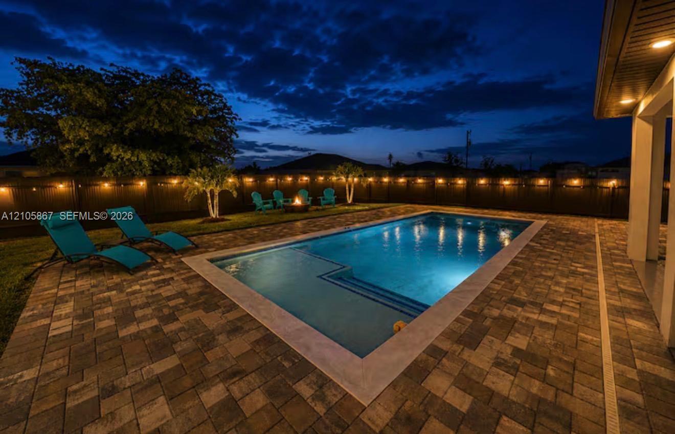 Backyard featuring a concrete-paved patio, rectangular in-ground pool with integrated entry steps, manicured lawn, and perimeter privacy fencing Backyard featuring a concrete-paved patio, rectangular in-ground pool with integrated entry steps, manicured lawn, and perimeter privacy fencing