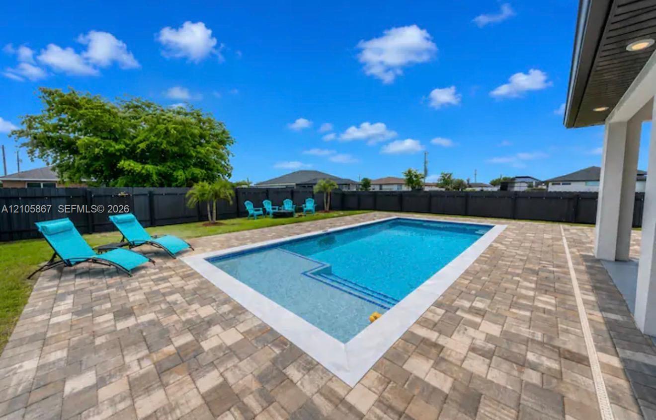 Backyard featuring an in-ground swimming pool with a tanning ledge, expansive paver patio, and full-perimeter privacy fencing Backyard featuring an in-ground swimming pool with a tanning ledge, expansive paver patio, and full-perimeter privacy fencing