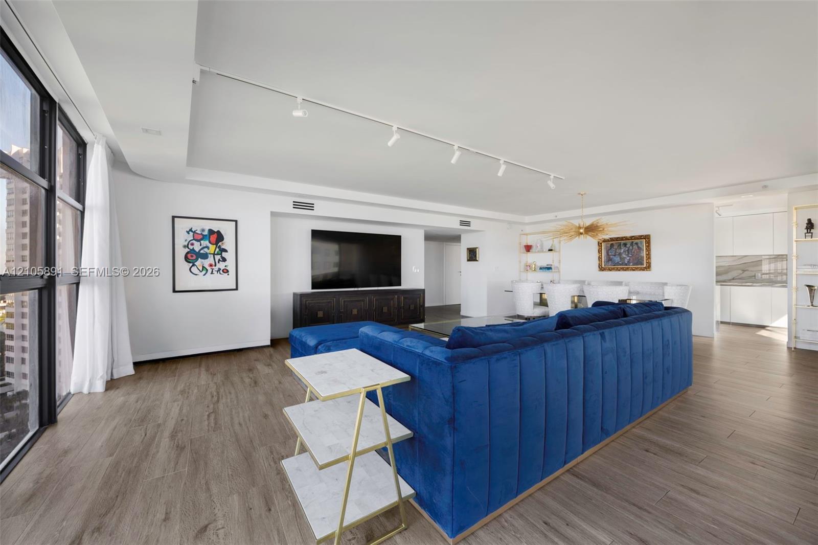 Expansive living area featuring floor-to-ceiling windows, wood-finish flooring, and recessed track lighting
