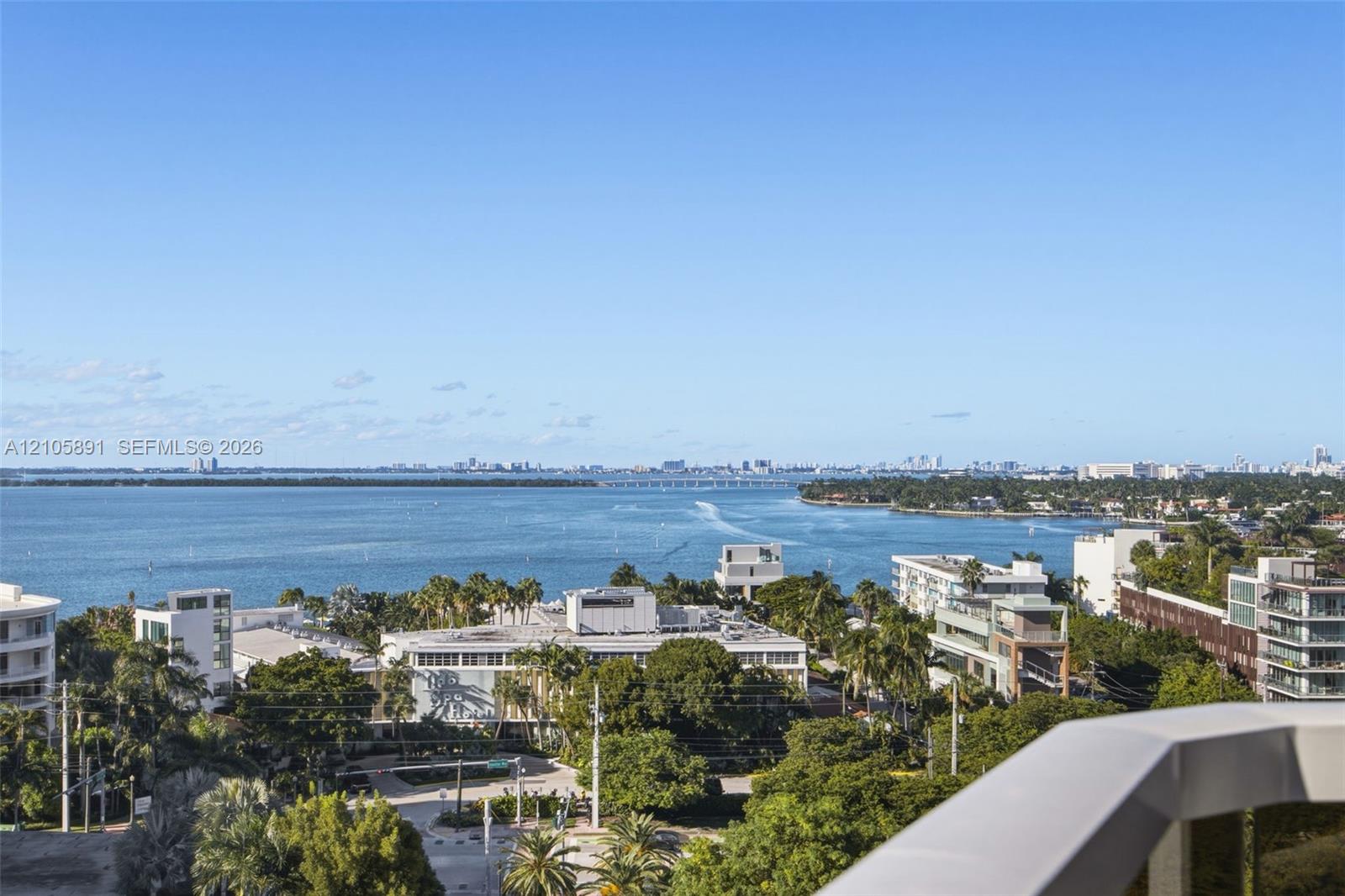 Elevated balcony with a solid white railing, offering expansive bay and coastal water horizon scenes