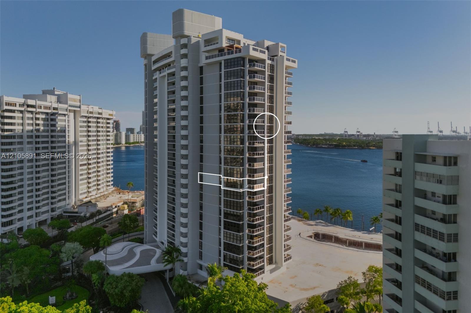 High-rise residential tower featuring a concrete facade, tiered architectural balconies, glass-paneled exterior walls, and a porte-cochere entrance