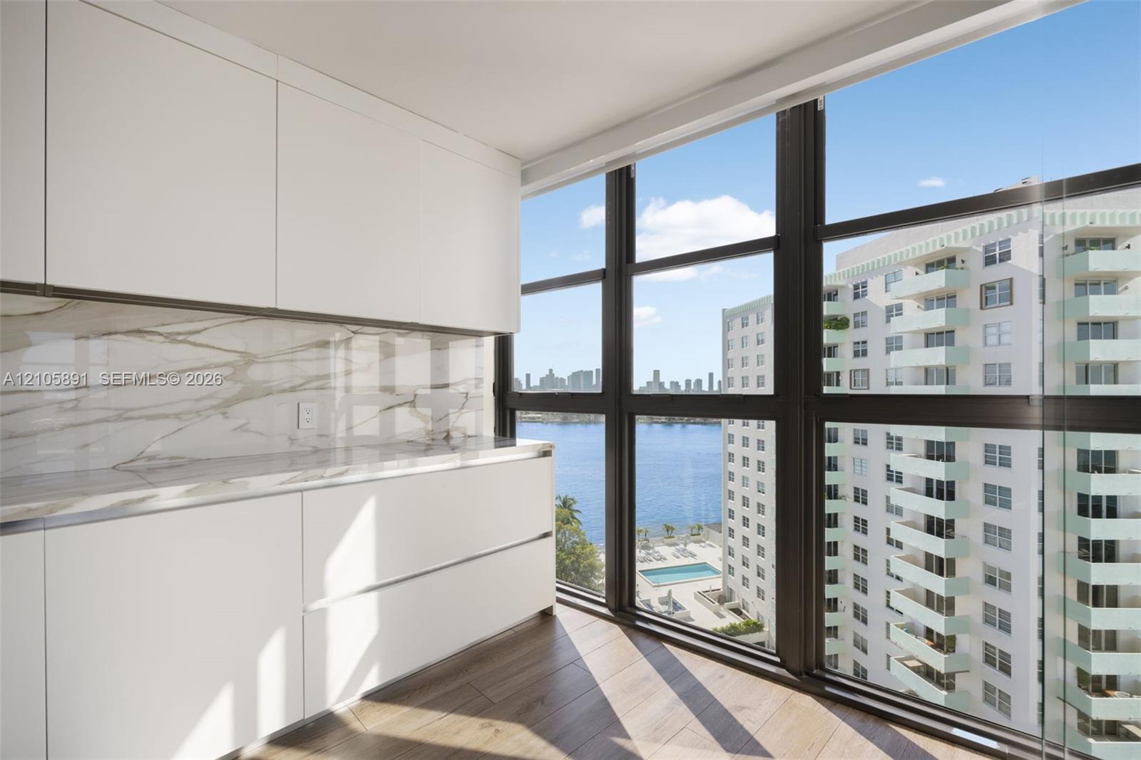 Sleek cabinetry with flat-panel doors, stone-patterned backsplash, expansive floor-to-ceiling windows, and wood-finish flooring