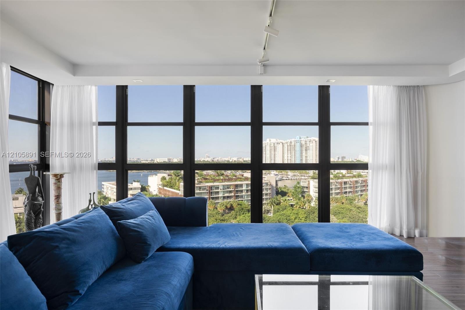 Floor-to-ceiling windows with dark-finish frames, wood-finish flooring, and track lighting