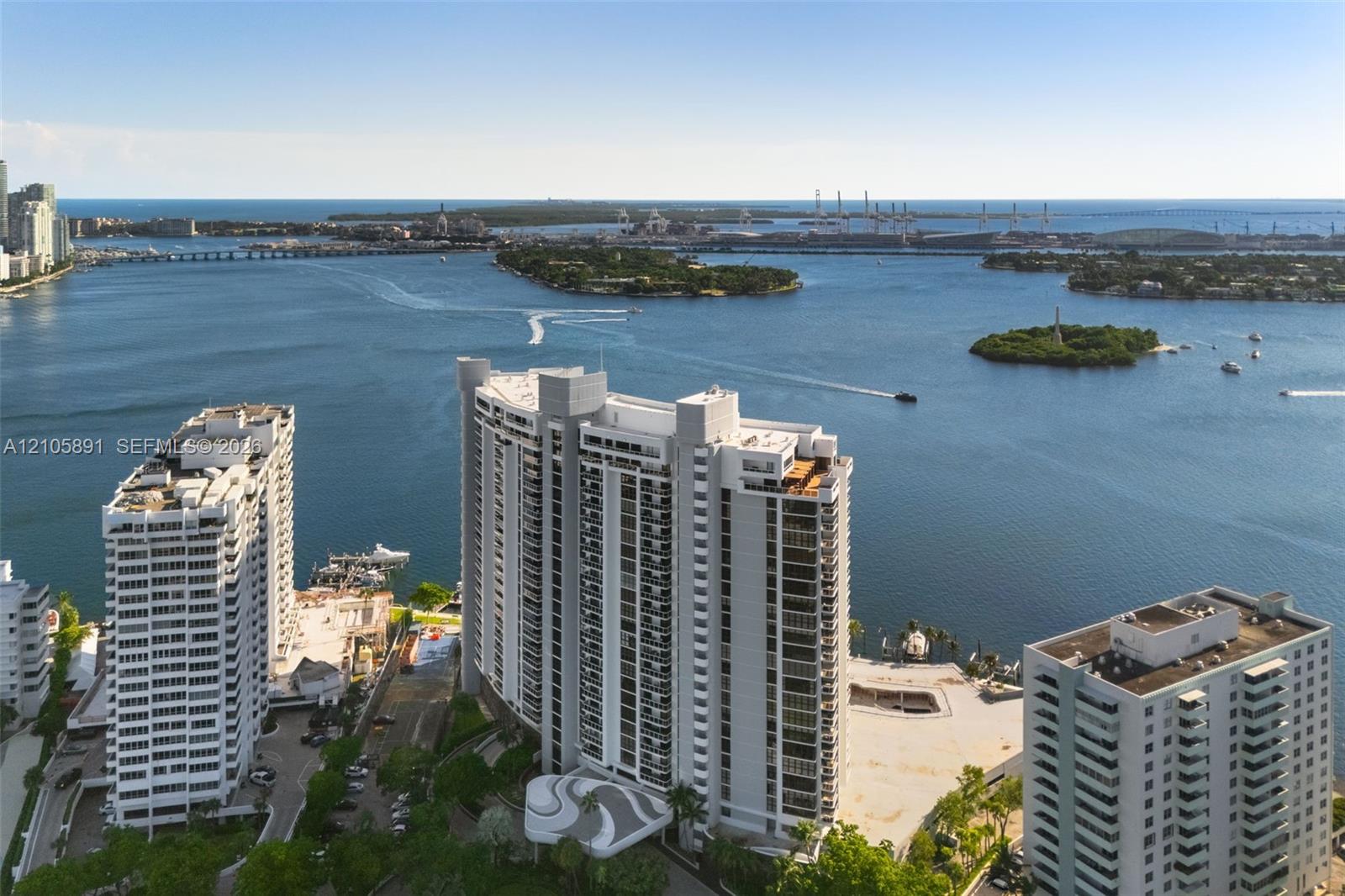 High-rise residential building featuring exterior balconies, a circular porte-cochre, and coastal surroundings