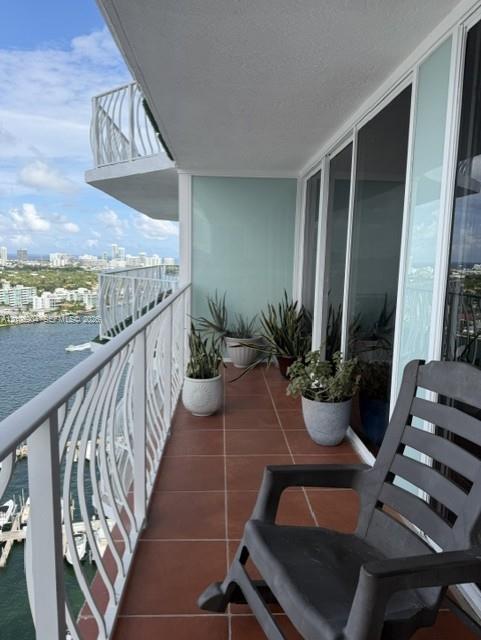 Covered balcony featuring tile flooring, white metal railings, and floor-to-ceiling glass sliding doors