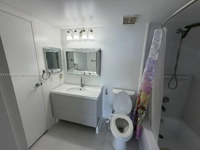 Bathroom featuring a gray vanity with an integrated sink, a beveled-edge mirror, a three-light vanity fixture, and a shower-tub combination with a handheld showerhead