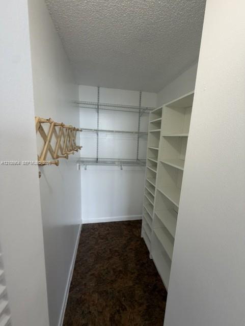 Storage space featuring white built-in shelving units, adjustable wire shelving, and a wall-mounted wooden accordion-style rack