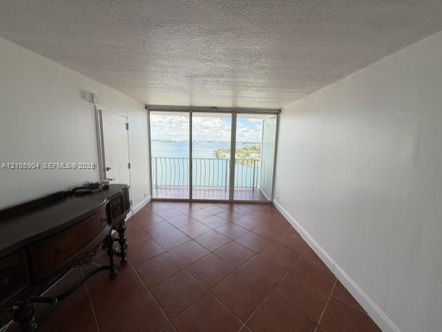 Ceramic tile flooring, floor-to-ceiling glass sliding doors, and a private balcony featuring a metal railing