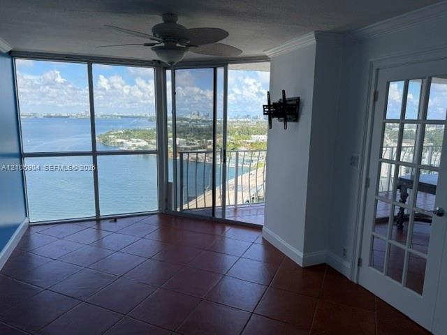 Floor-to-ceiling windows featuring panoramic water scenery, large-format tile flooring, sliding glass doors, a ceiling fan, and a French-style door Floor-to-ceiling windows featuring panoramic water scenery, large-format tile flooring, sliding glass doors, a ceiling fan, and a French-style door