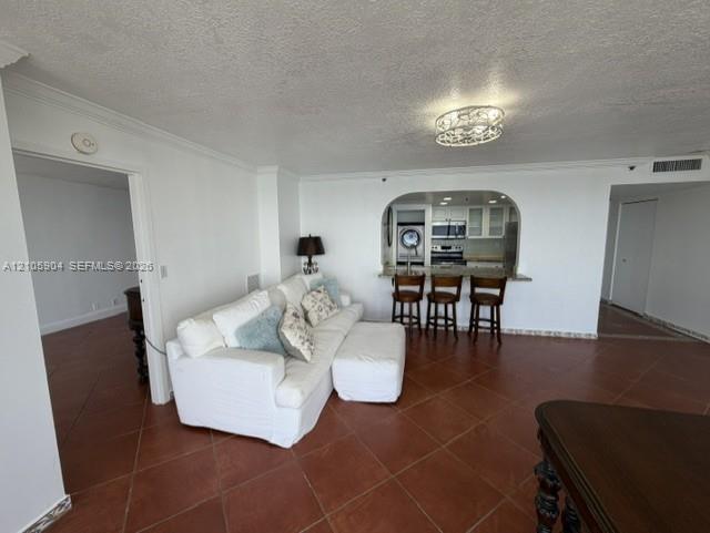 Interior featuring terracotta-style tile flooring, arched wall opening, breakfast bar, and decorative ceiling-mounted light fixture