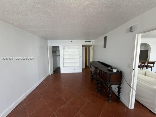 Interior space featuring large-format ceramic tile flooring, built-in shelving, and a walk-in closet with integrated storage rack