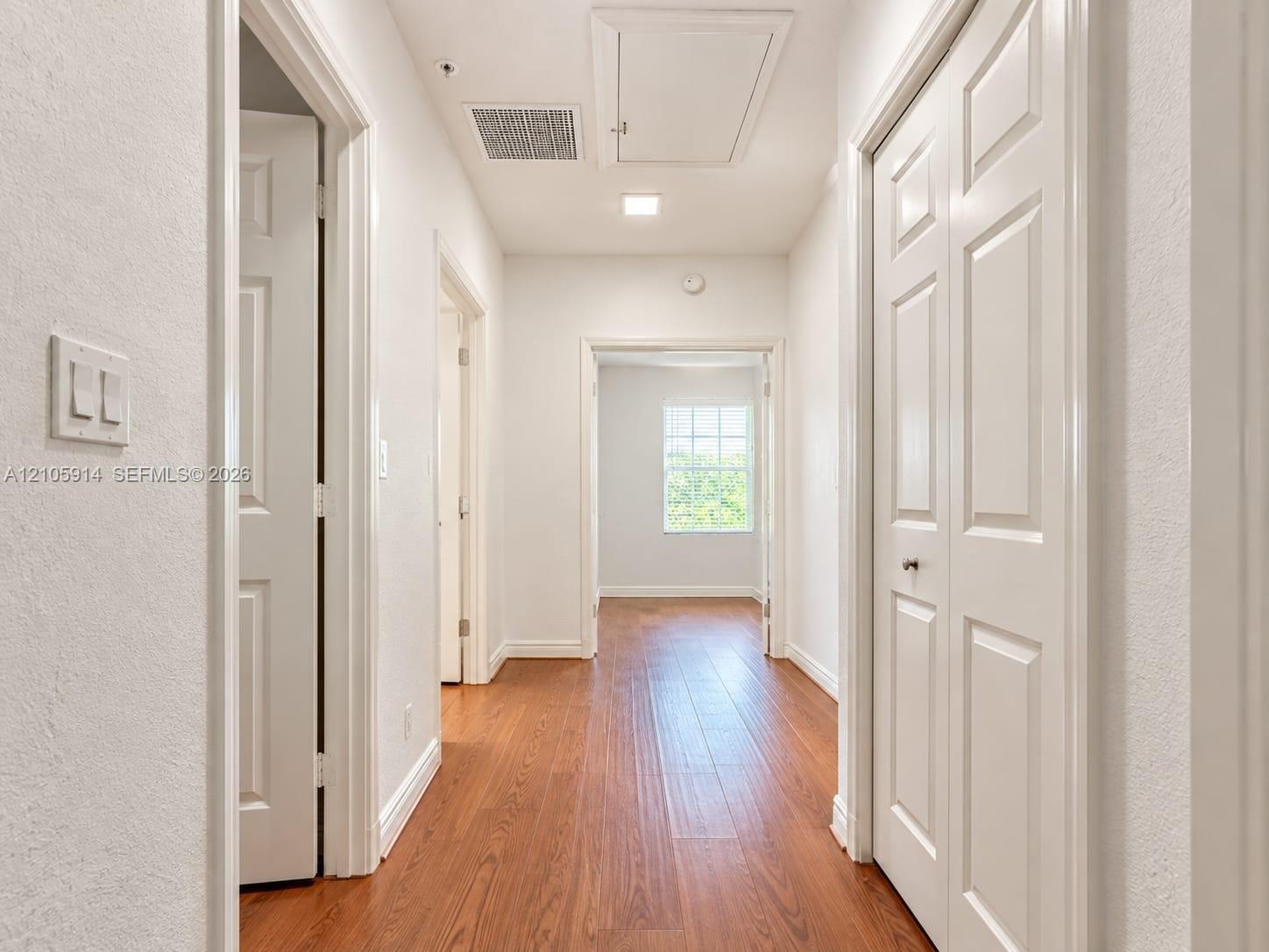 Hallway featuring wood-finish flooring, white panel doors, and recessed lighting