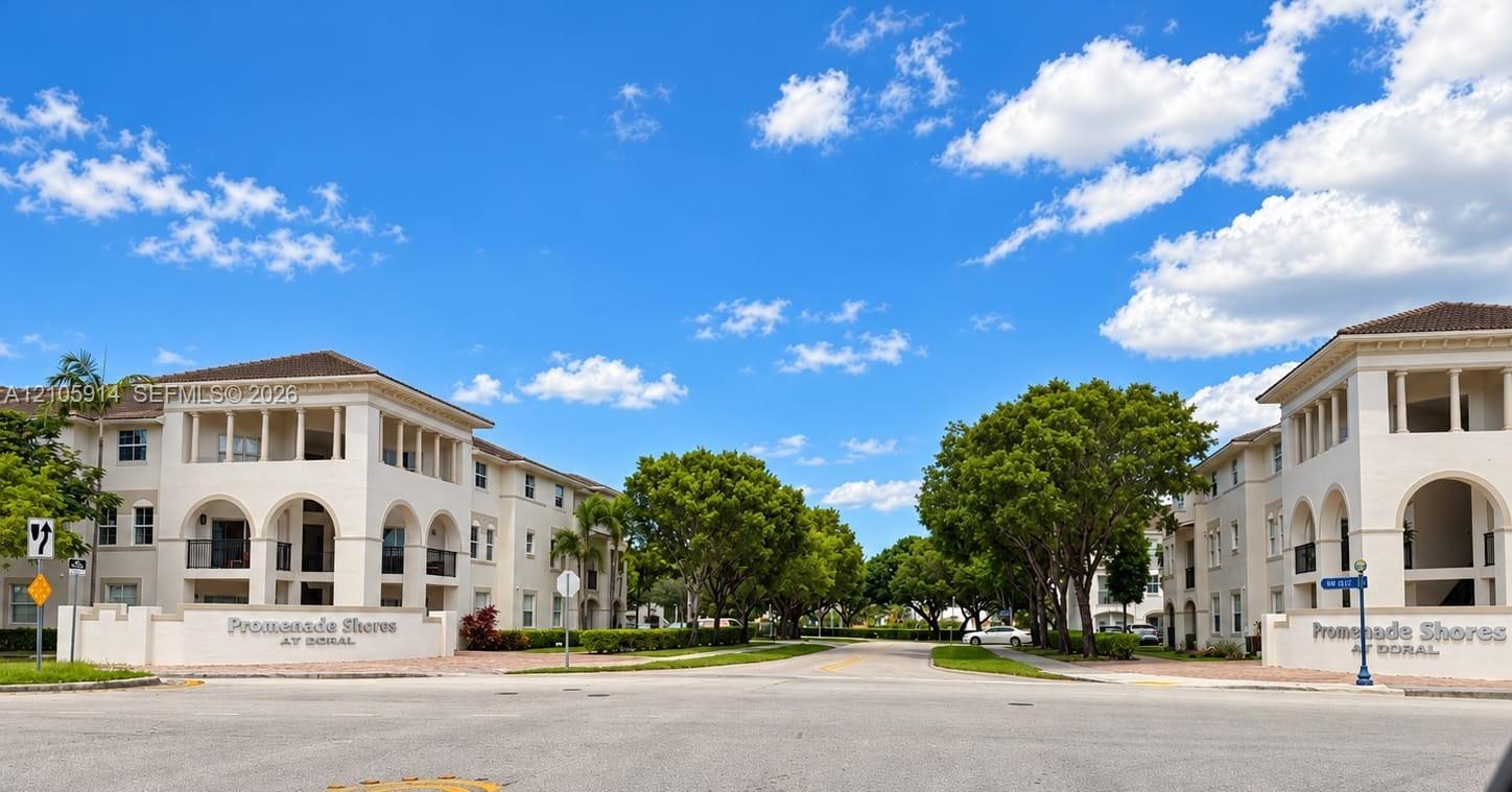 Multi-story residential complex featuring Mediterranean-inspired architectural elements, arched exterior colonnades, stucco facades, and mature landscaping