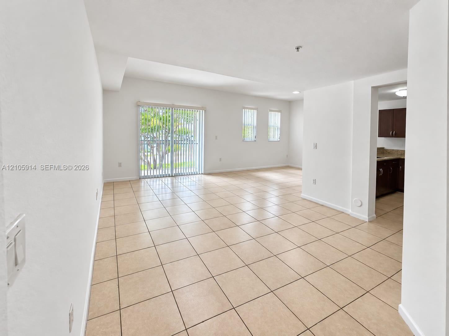 Open-concept interior featuring neutral tile flooring, sliding glass patio doors, and recessed lighting