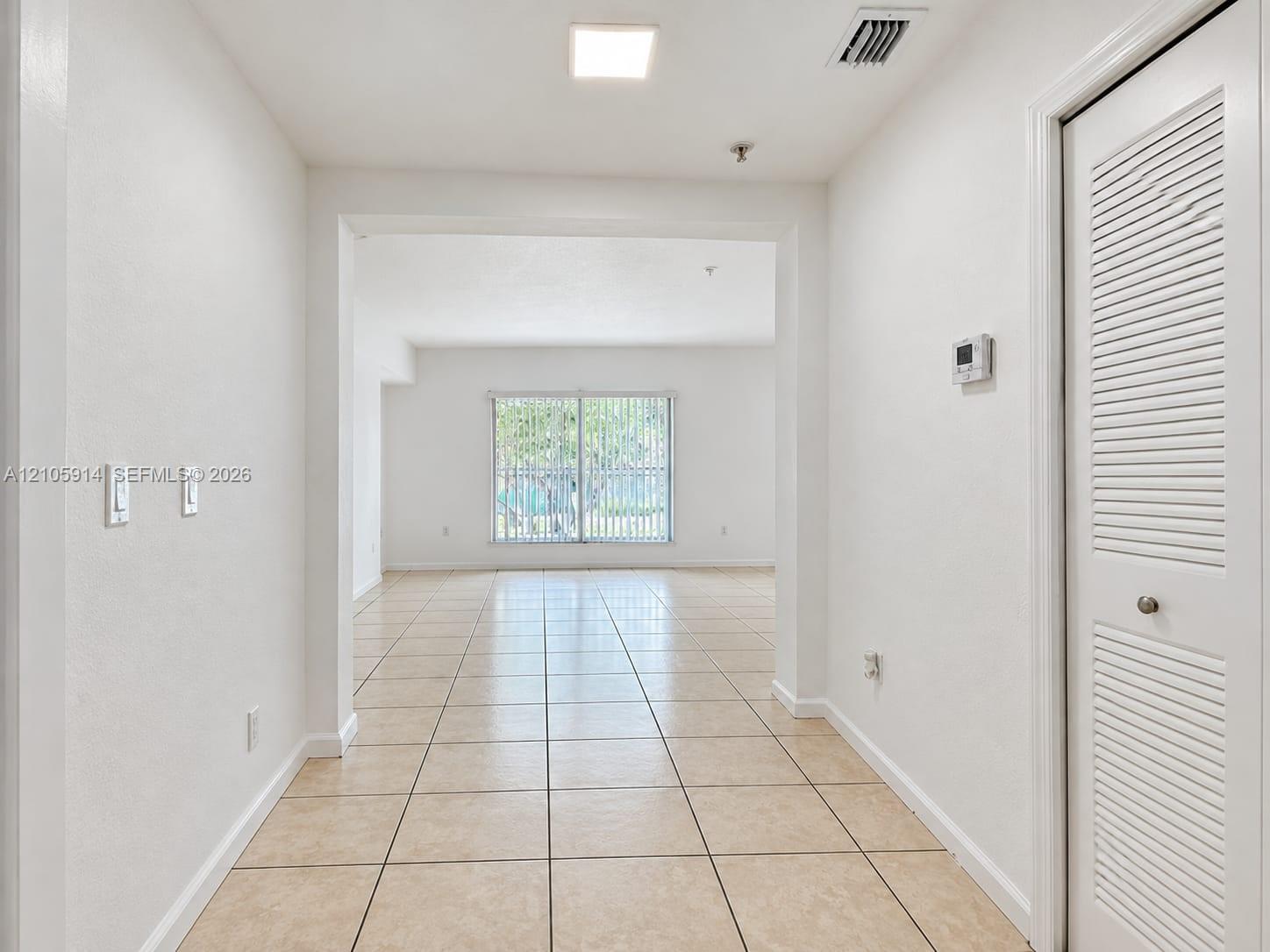 Interior space featuring large-format ceramic tile flooring, neutral wall finishes, recessed ceiling lighting, and a closet with bifold louvered doors