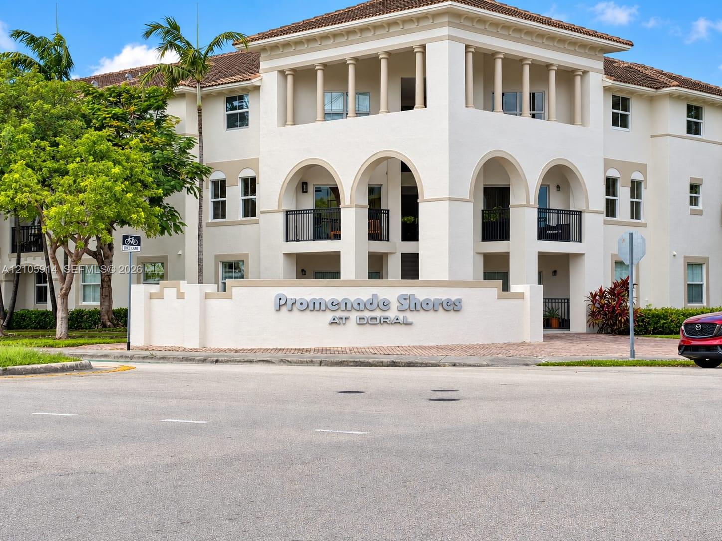 Mediterranean-inspired exterior architecture featuring arched entryways, multi-level balconies with black metal railings, and decorative columns