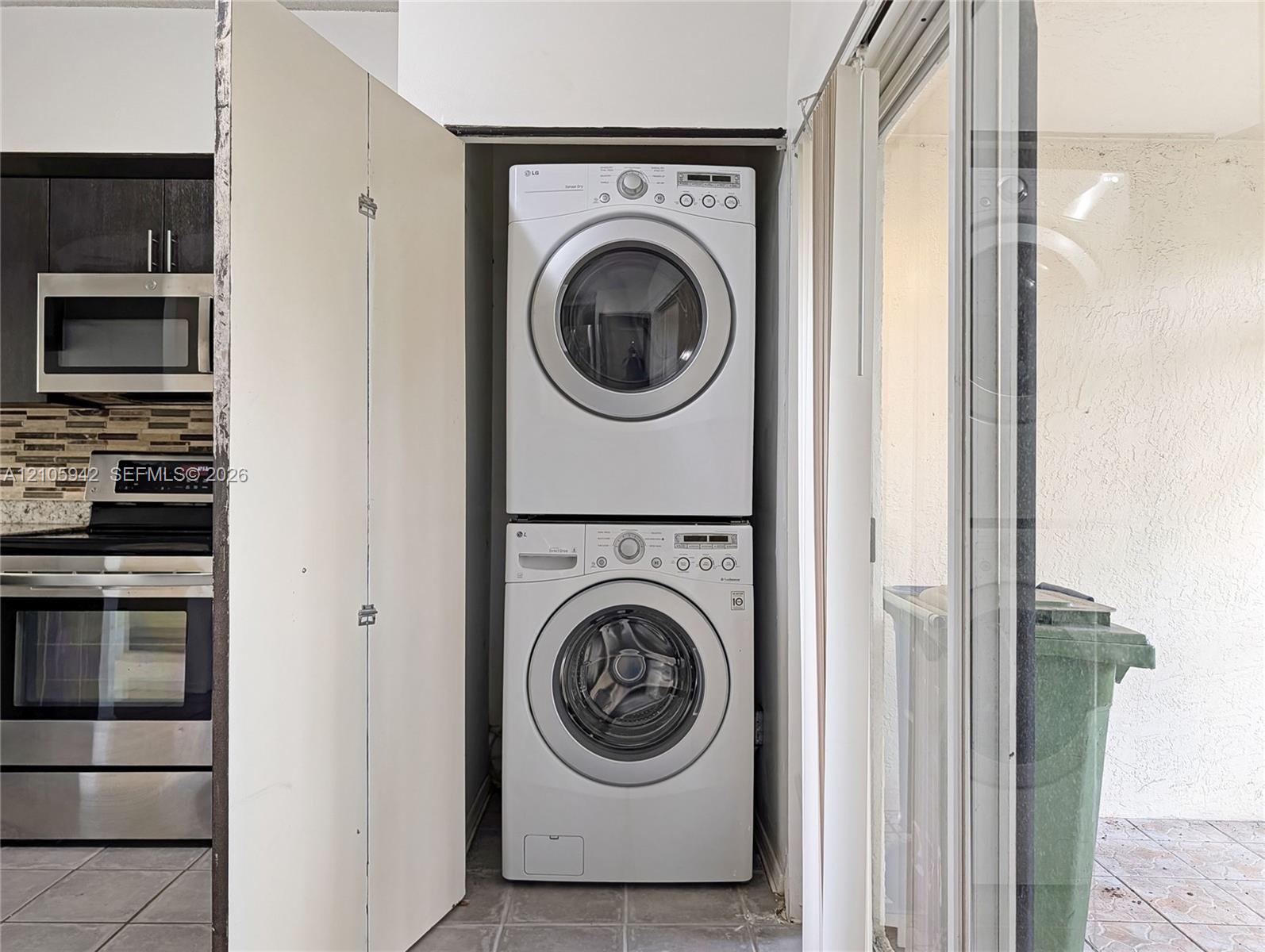 Stacked washer and dryer unit, stainless steel microwave, stainless steel range, and tile flooring