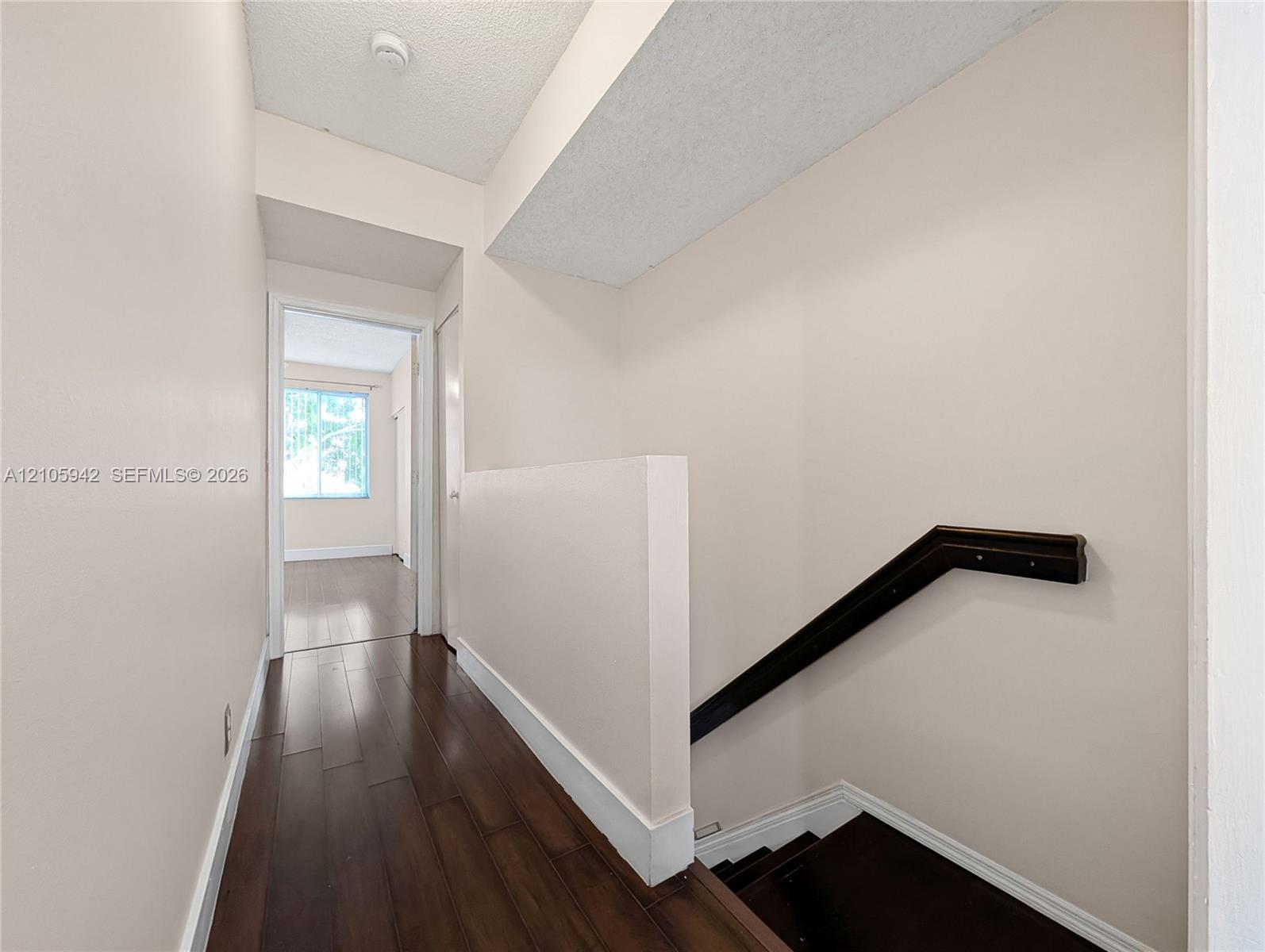 Wood-finish flooring, half-wall staircase enclosure, and dark wood handrail