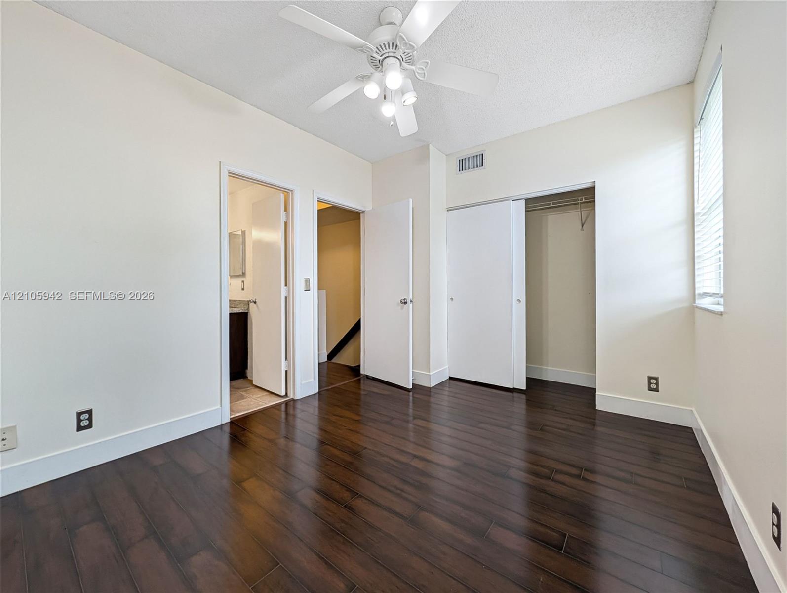 Wood-finish flooring, ceiling fan with integrated lighting, window with horizontal blinds, and sliding closet doors