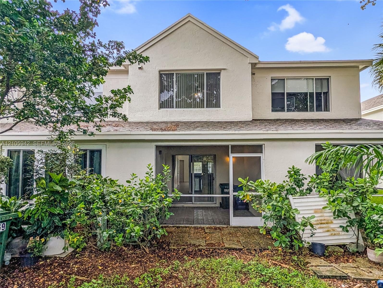 Rear exterior featuring a covered patio, stucco siding, multi-level design, and private chain-link fencing