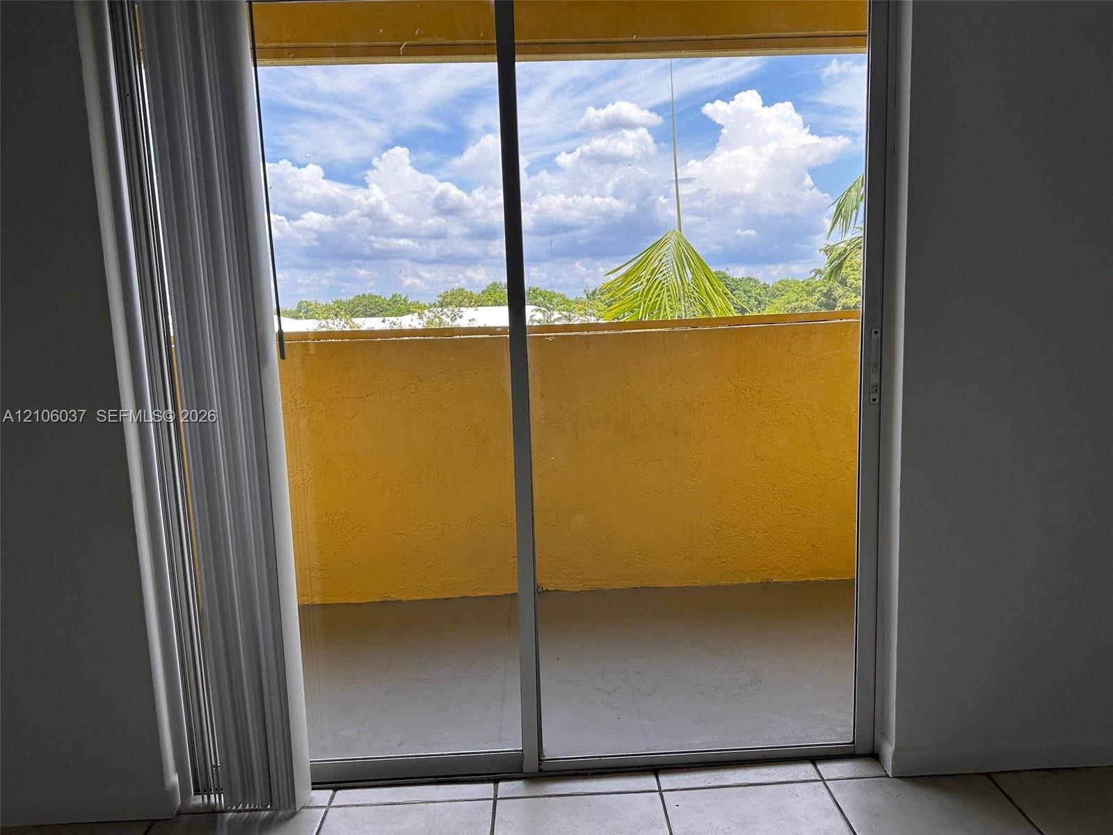 Sliding glass door opening to a private balcony with solid masonry railings and ceramic tile flooring